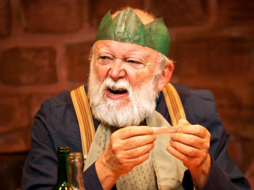 A grumpy Father Christmas reads a joke from a Christmas cracker.