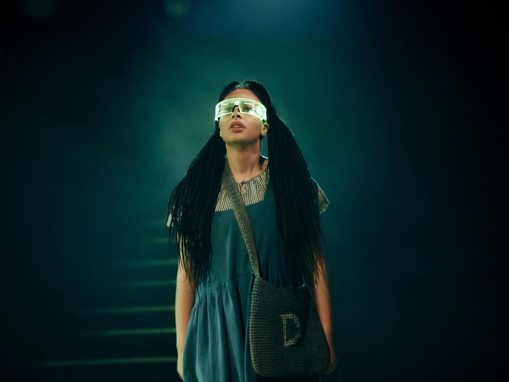 Dorothy, alone, wearing green goggles.