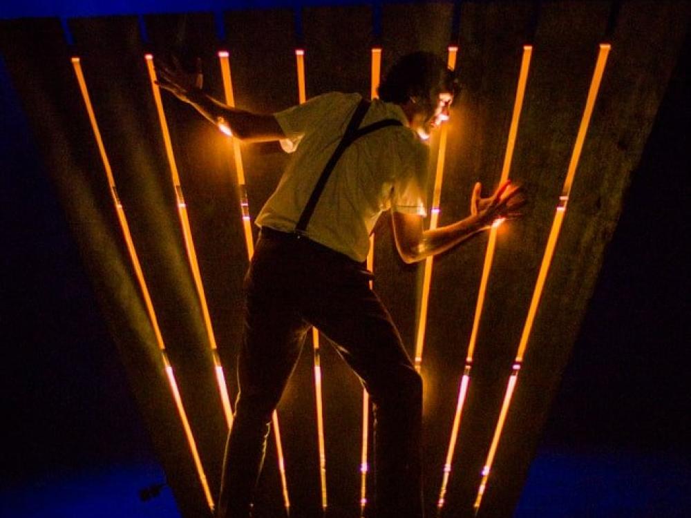 A man listens intently through the floorboards which glow eerily. 