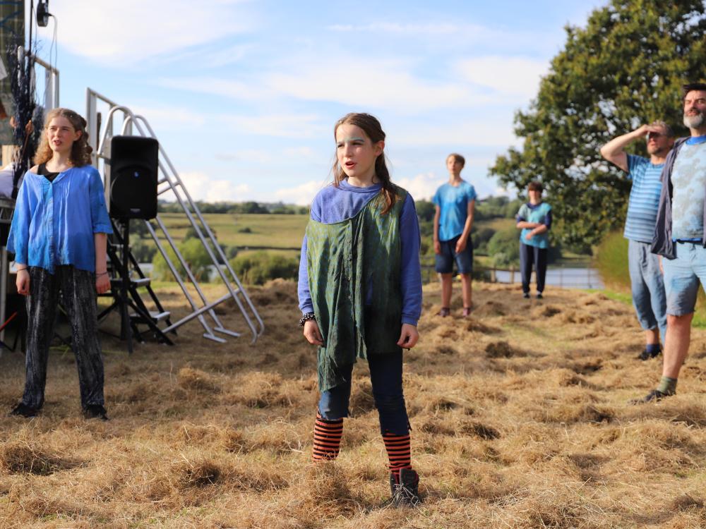 Cast of Rising Waters stand on grass in front of a lake
