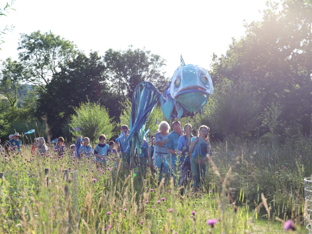 Cast of Rising Waters stand on grass in front of a lake