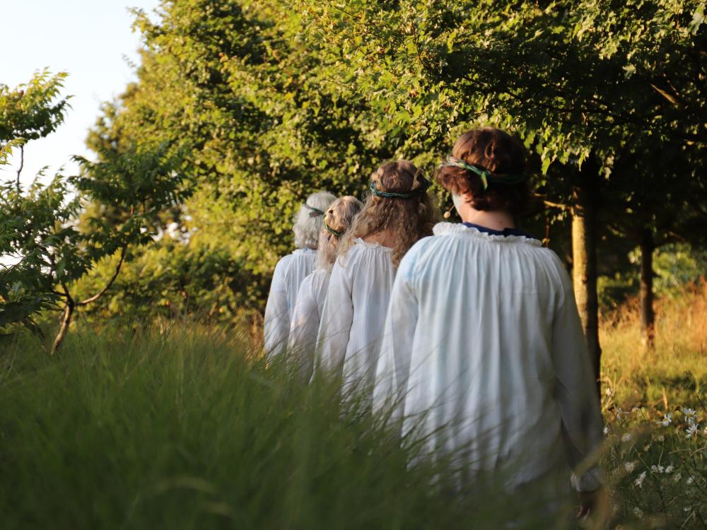 Cast of Rising Waters stand on grass in front of a lake