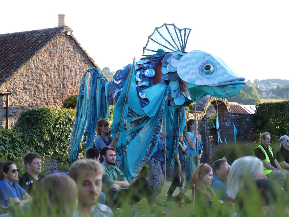Cast of Rising Waters stand on grass in front of a lake