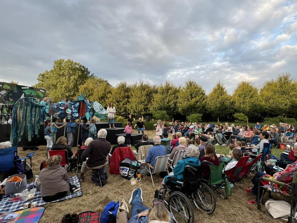 Cast of Rising Waters stand on grass in front of a lake