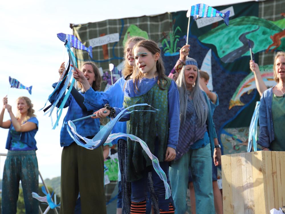 Cast of Rising Waters stand on grass in front of a lake