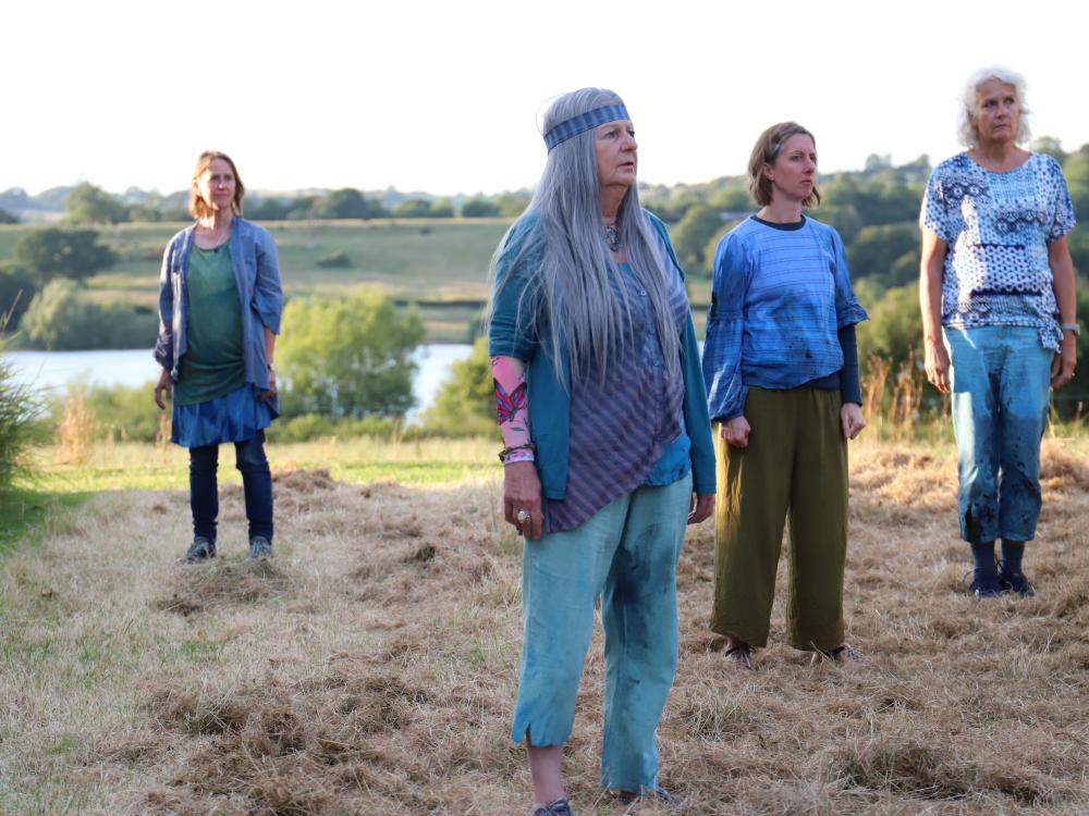 Cast of Rising Waters stand on grass in front of a lake