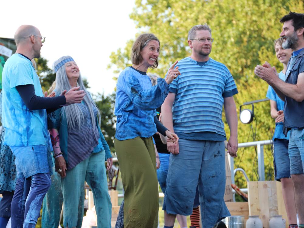 Cast of Rising Waters stand on grass in front of a lake
